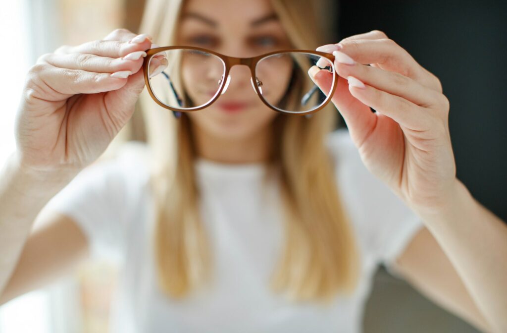 A young woman holding a pair of glasses in front of her