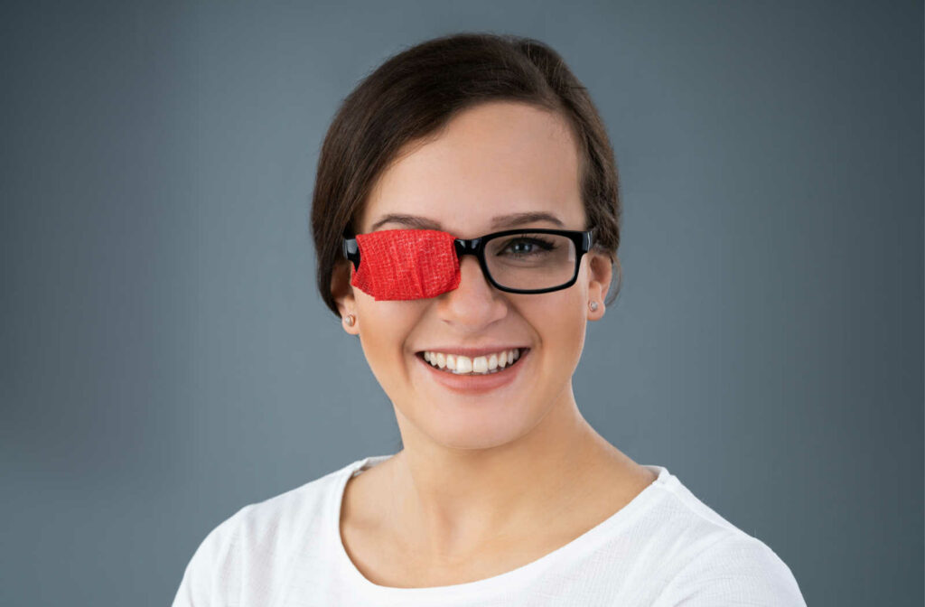 Portrait of a middle aged smiling woman wearing a pair of glasses with a red occluder over the right eye.